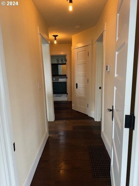 corridor with dark hardwood / wood-style floors and a textured ceiling