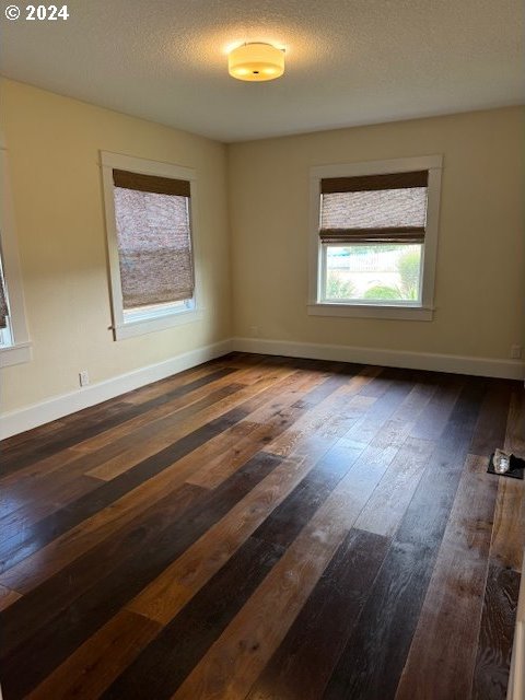 empty room with a textured ceiling and dark hardwood / wood-style flooring