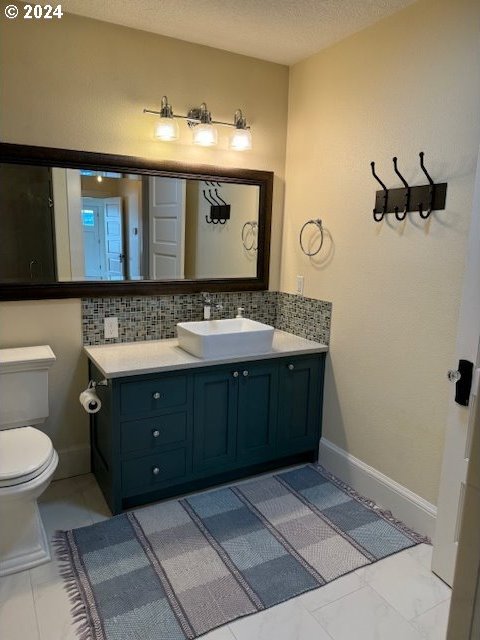 bathroom featuring backsplash, tile patterned floors, vanity, and toilet