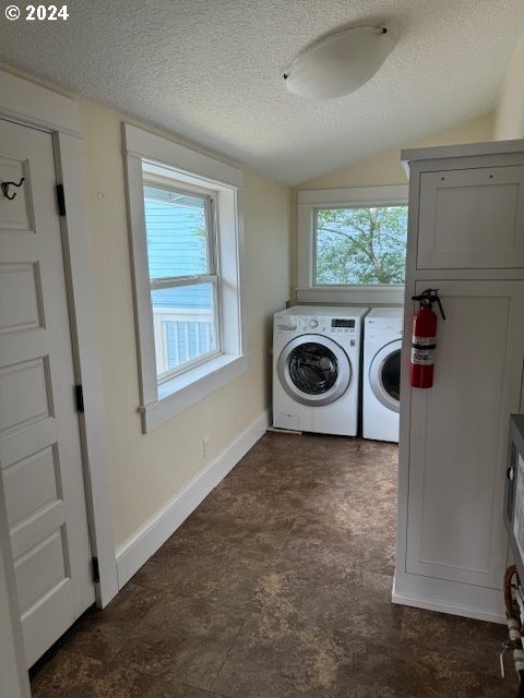 laundry room with dark tile patterned floors, a textured ceiling, and washing machine and clothes dryer