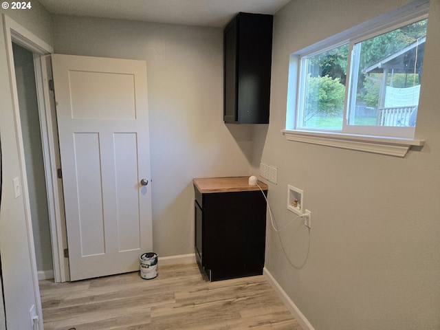 clothes washing area with hookup for a washing machine, light hardwood / wood-style floors, and cabinets