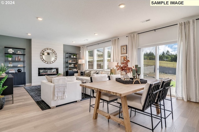 dining space featuring light wood-type flooring and a large fireplace