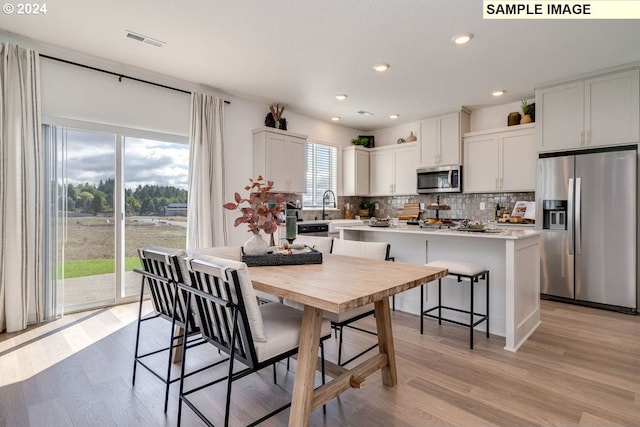 kitchen featuring white cabinets, appliances with stainless steel finishes, a center island, and light hardwood / wood-style floors