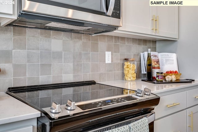 kitchen featuring backsplash, white cabinetry, electric range, and light stone counters