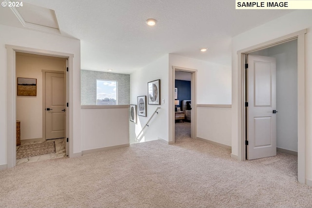 hallway featuring a textured ceiling and light colored carpet