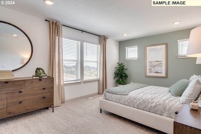 bedroom with light colored carpet and a textured ceiling