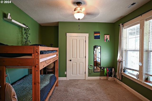 bedroom featuring carpet flooring, ceiling fan, and a textured ceiling