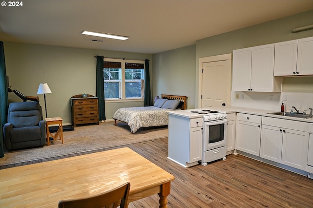 kitchen with white cabinetry, sink, white range oven, kitchen peninsula, and hardwood / wood-style flooring