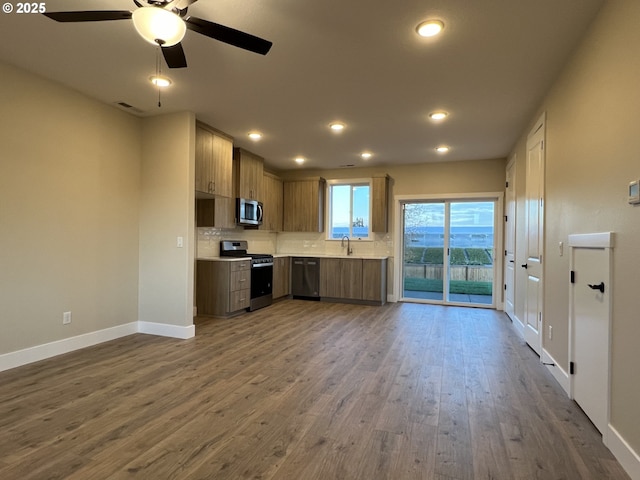 kitchen with sink, backsplash, ceiling fan, stainless steel appliances, and dark wood-type flooring