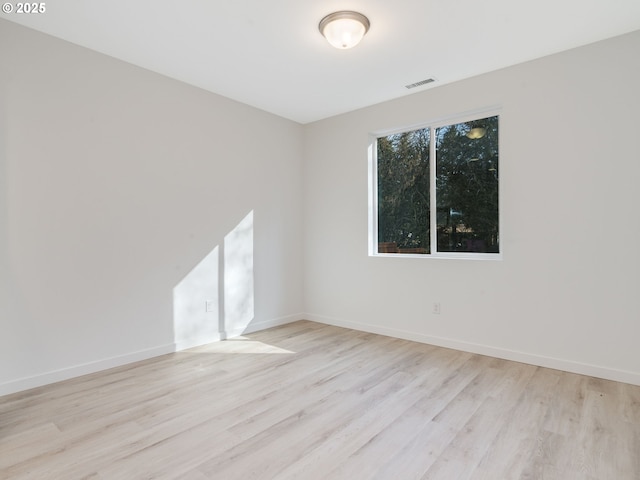 empty room with visible vents, light wood-style flooring, and baseboards