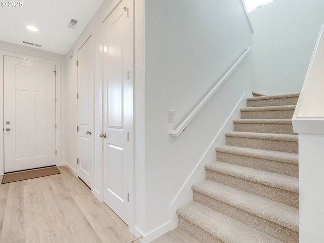 stairs featuring wood finished floors, visible vents, and baseboards