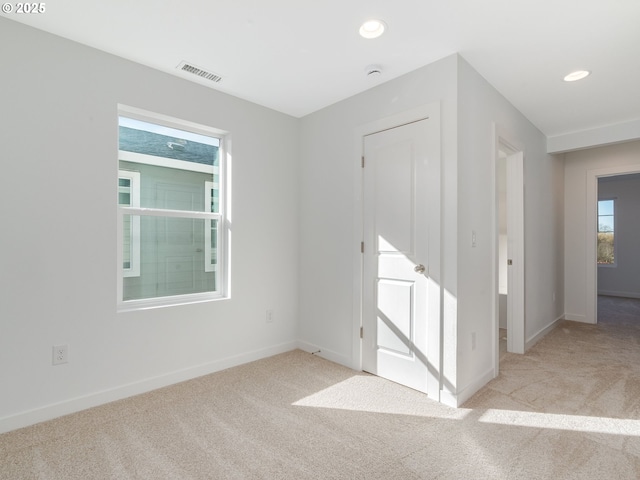 carpeted empty room with baseboards, visible vents, and recessed lighting