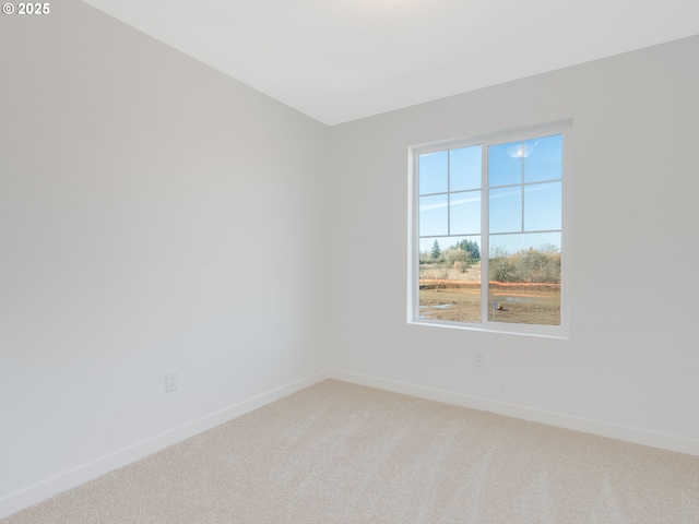 unfurnished room featuring baseboards and light colored carpet