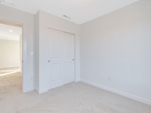 unfurnished bedroom with carpet floors, baseboards, visible vents, and a closet