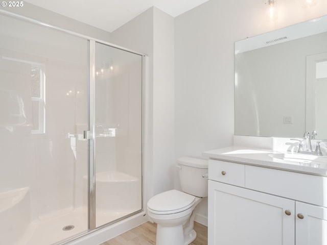 bathroom featuring a stall shower, visible vents, toilet, wood finished floors, and vanity