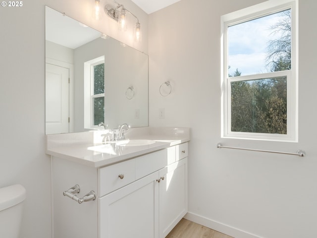 bathroom featuring toilet, baseboards, wood finished floors, and vanity