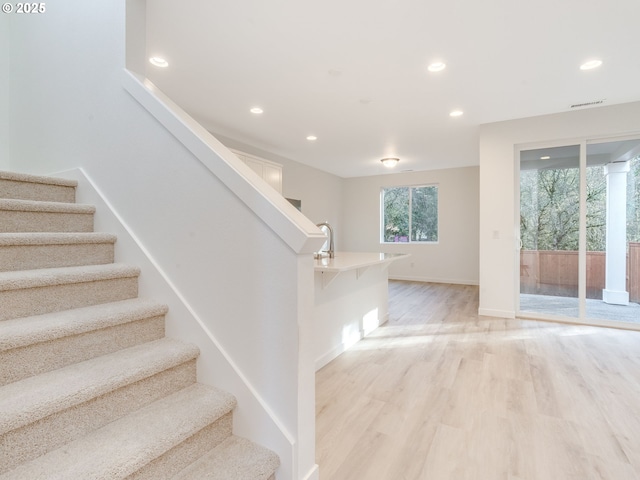 stairway featuring baseboards, visible vents, wood finished floors, and recessed lighting