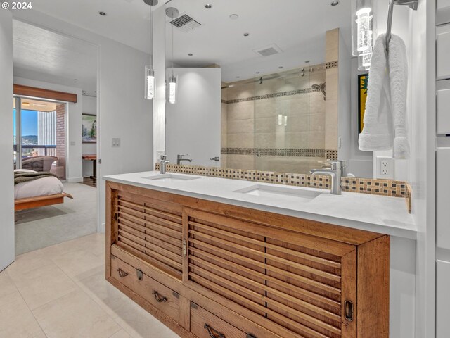 bathroom featuring vanity, a tile shower, and tile patterned flooring