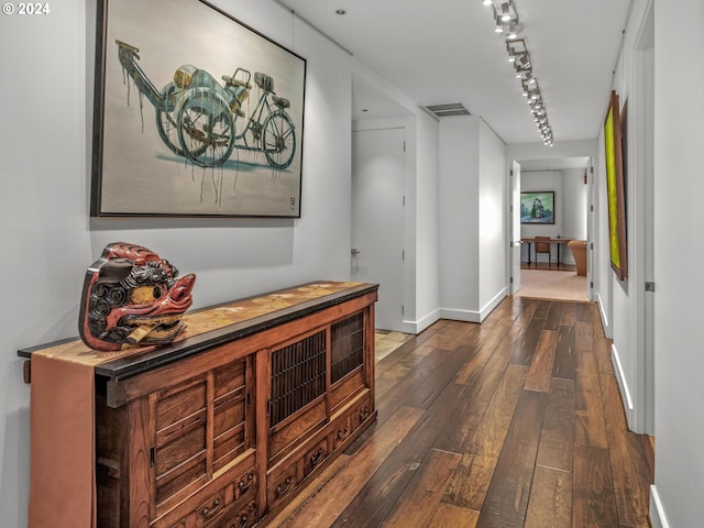 corridor featuring rail lighting and dark hardwood / wood-style floors