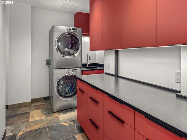 laundry area featuring stacked washing maching and dryer, cabinets, and sink