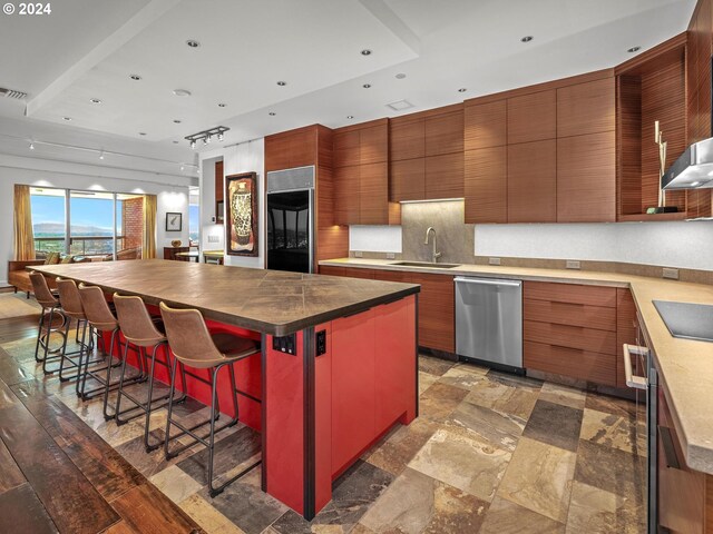 kitchen featuring a kitchen island, a kitchen breakfast bar, black appliances, backsplash, and sink