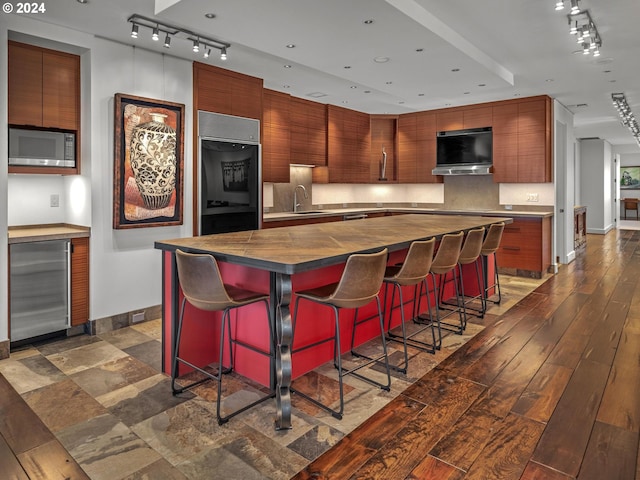 kitchen with stainless steel appliances, dark hardwood / wood-style flooring, a kitchen island, sink, and a breakfast bar area