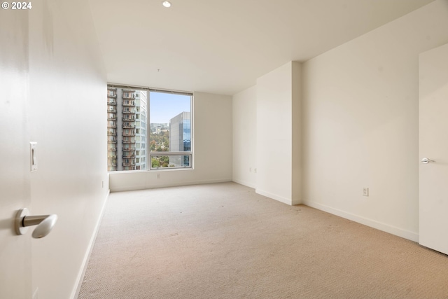 empty room with baseboards, a city view, and carpet flooring