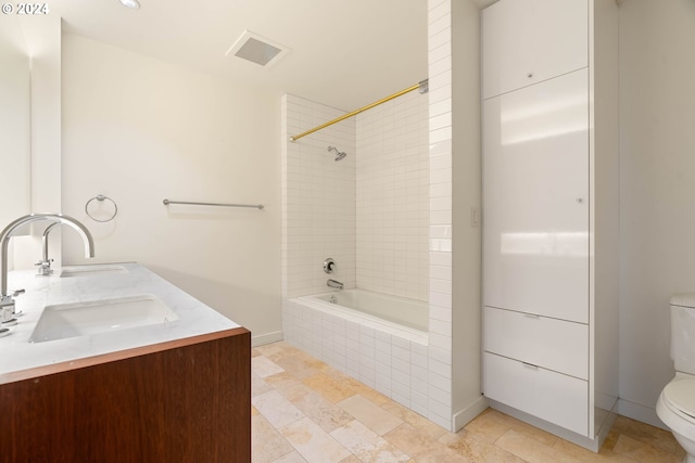 full bath with double vanity, visible vents, toilet, tiled shower / bath combo, and a sink