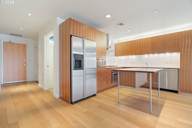 kitchen featuring appliances with stainless steel finishes, light hardwood / wood-style flooring, backsplash, and kitchen peninsula