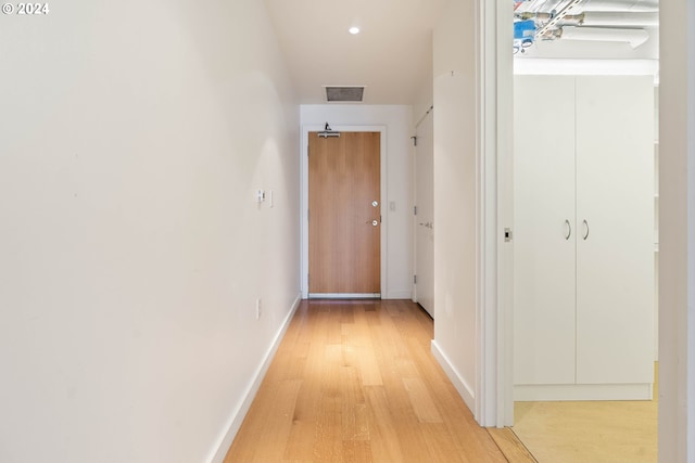 corridor featuring light wood finished floors, visible vents, and baseboards