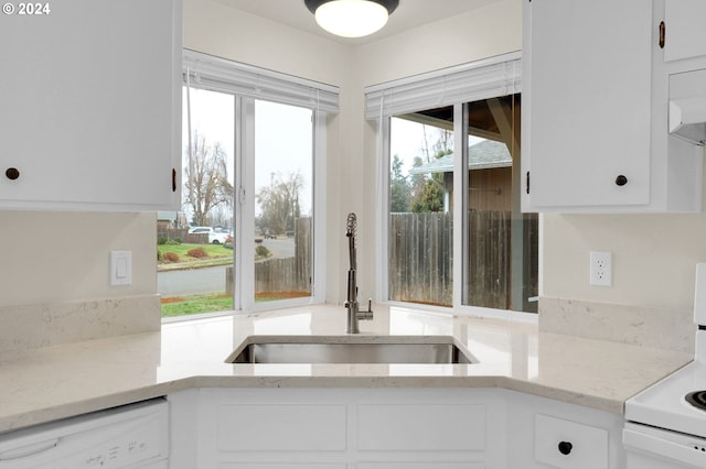 kitchen with light stone counters, sink, white cabinets, and white appliances