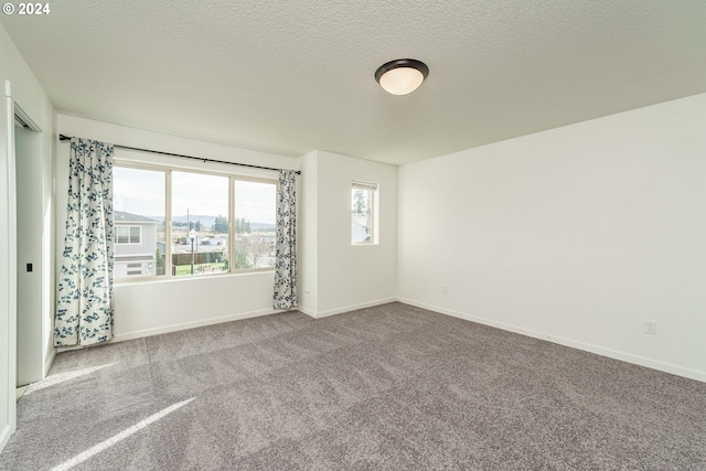 carpeted spare room with a textured ceiling