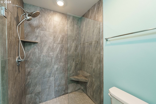 bathroom featuring tiled shower and toilet