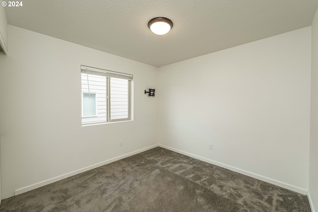 unfurnished room featuring a textured ceiling and dark carpet