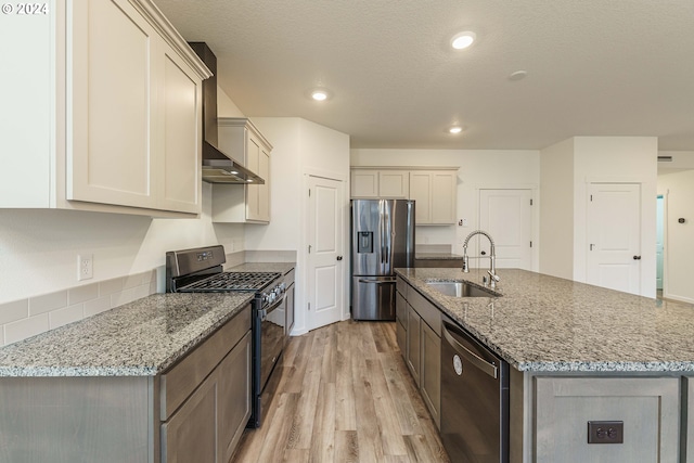 kitchen featuring light stone countertops, an island with sink, stainless steel appliances, and sink