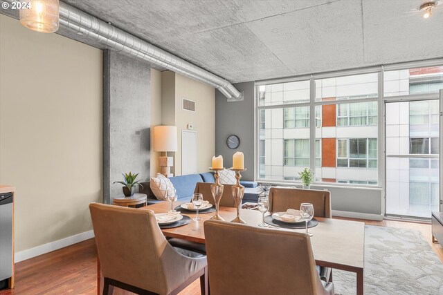 dining space with a wealth of natural light, hardwood / wood-style floors, and a wall of windows