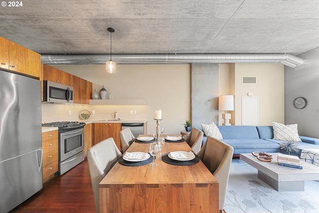 kitchen with wood counters, sink, hanging light fixtures, a kitchen island, and stainless steel appliances