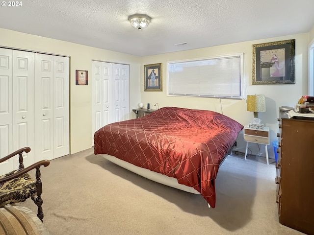 bedroom featuring a textured ceiling, two closets, and carpet floors