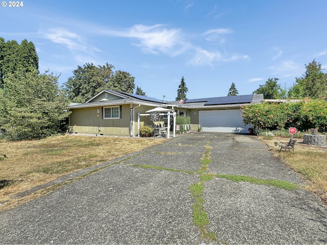 single story home with a garage and solar panels