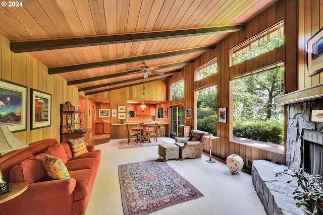 living room featuring carpet flooring, vaulted ceiling with beams, wood walls, and ceiling fan