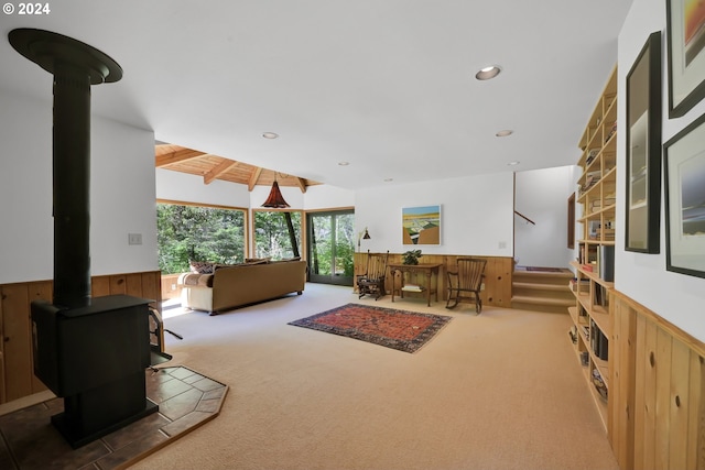 carpeted living room with a wood stove and wooden walls