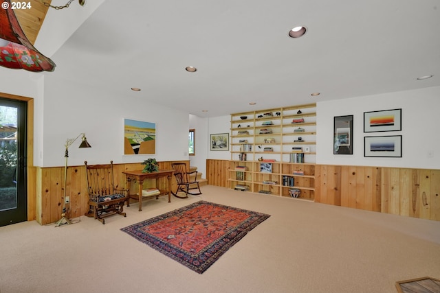 sitting room with carpet, plenty of natural light, and wooden walls