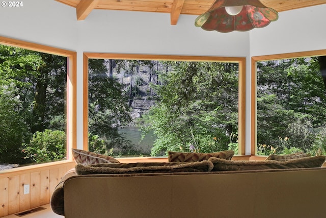 unfurnished sunroom featuring beamed ceiling, ceiling fan, a water view, and wood ceiling