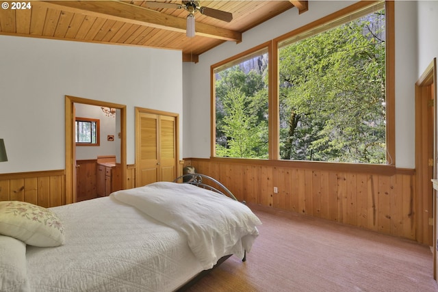 bedroom featuring wood walls, wooden ceiling, ceiling fan, carpet floors, and a closet