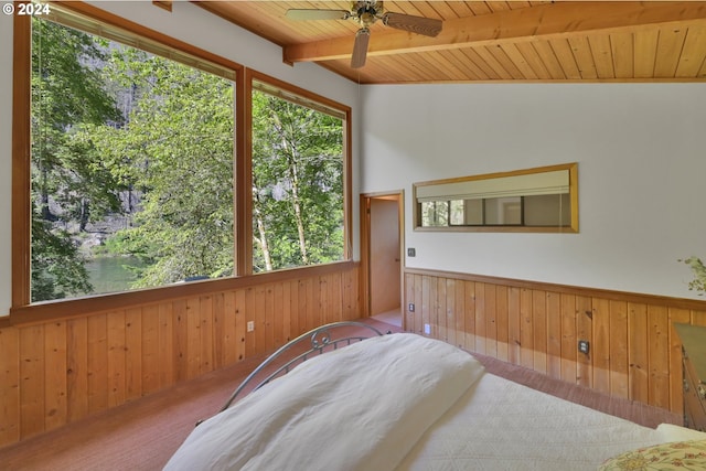 carpeted bedroom featuring lofted ceiling with beams, wood walls, and wooden ceiling