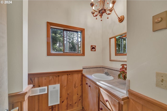 bathroom featuring wooden walls, vanity, and an inviting chandelier