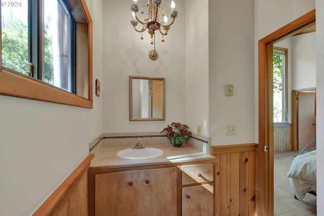 bathroom with wooden walls, vanity, and a chandelier