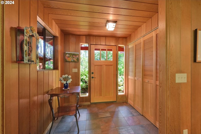 foyer entrance with wooden walls and wooden ceiling