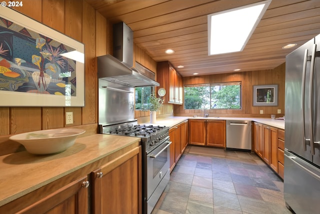 kitchen with appliances with stainless steel finishes, wooden walls, sink, wall chimney range hood, and wooden ceiling