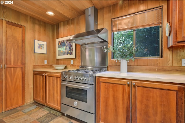 49356 Mckenzie Hwy, Vida, OR 97488 - kitchen featuring stainless steel gas range, wall chimney range hood, brown cabinetry, wood walls, and light countertops